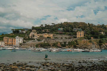 Fototapeta premium Scenic marina view of monument Il Pescatore of the Leonardo Lustig in the bay of the Silence in Sestri Levante, Liguria, Italy across the colorful houses, mountains and coastline