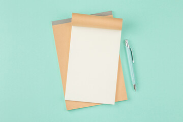 Open notepad with pen on green background