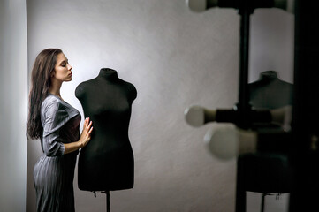 young girl model standing leaning on mannequins, fashion designer in her office near mirror