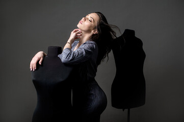 young girl model, fashion designer in his office dreams leaning on mannequins