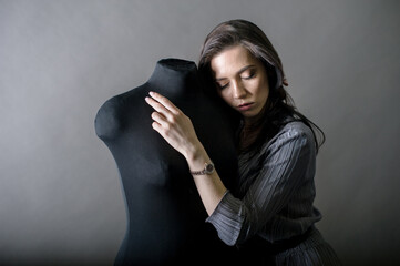 young girl model, fashion designer in her office, leaning on mannequins in the plan and dreams