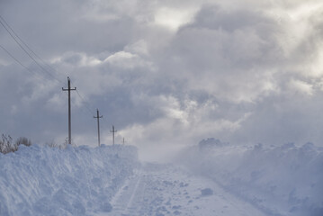 A deserted country road through snow-covered fields.