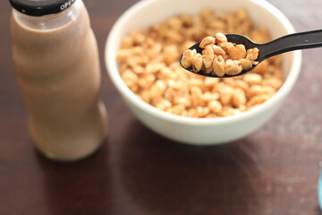 cereal in a white cup with chocolate milk in a ready-to-eat glass jar Served on a brown wooden table.