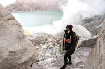 Female traveler standing on edge of active volcano with acid lake and sulfur gas fumes in Java, Indonesia © Space_Cat