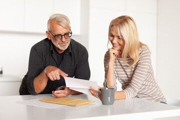A happy couple looks at the postal bills. Mature man and woman received feedback.