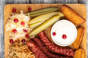 set of snacks: sausages, toast, sauerkraut, marinated onion and cucumber, baked potato. Top view.