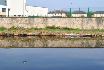 Reflection of Buildings and Stone Wall in Still Waters of Canal