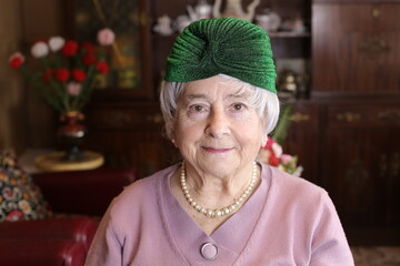 Cute granny wearing green shiny turban and pearls necklace