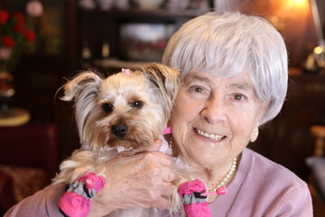 Senior woman holding little dog with pink shoes