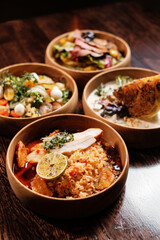Several restaurant dishes in round wooden plates. Spicy chicken with rice and lime.