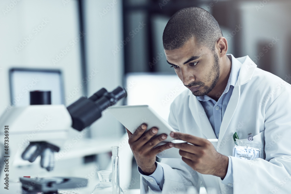 Poster using his tablet for research purposes. shot of a scientist recording his findings on a digital tabl