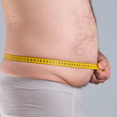 Man measuring his fat and hairy belly with a tap measure, profile photo, close up look