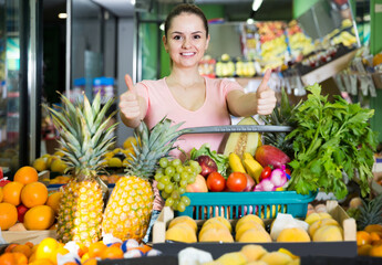 Young spanish woman with basket with fresh greengrocery enjoying purchases in vegetable store