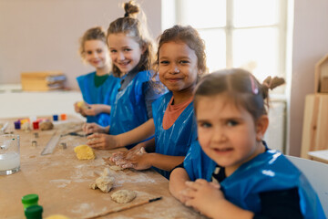Group of little kids working with pottery clay during creative art and craft class at school.