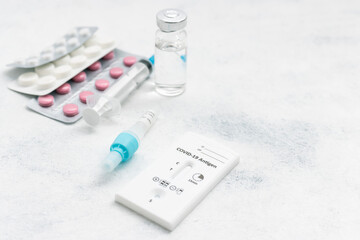 Rapid antigen test kit for viral disease COVID-19, medicine treatment, pills and glass vial on a white background