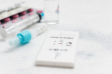 Rapid antigen test kit for viral disease COVID-19 with negative result, medicine treatment, pills and glass vial on a white background