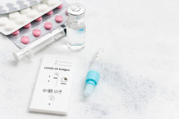Rapid antigen test kit for viral disease COVID-19 with negative result, medicine treatment, pills and glass vial on a white background