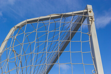Corner of football goal. Triangle with Net of goal in soccer field at evening time - close up