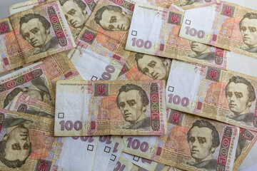 Ukrainian paper money is laid out on a blue background. 100 hryvnia banknotes