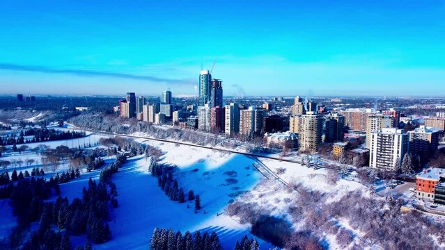 Aerial flyover birds view Victoria park snow covered towards the luxury residential downtown Westside residential buildings on the hilltop cliff edge stunning winter sunny blue clear sky afternoon