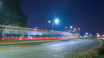 Light trails in a curve, with a city in the background.