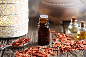 A bottle of sandalwood essential oil with red sandalwood chips
