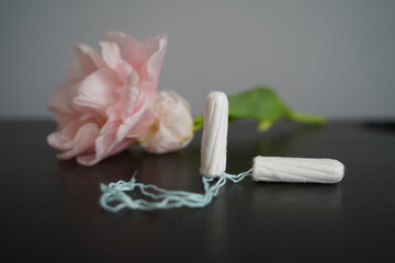 a female tampon for menstruation next to a flower on a gray background
