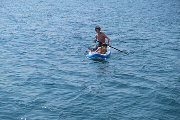 A young sports man with a child sails on a sup in the sea. Healthy lifestyle concept