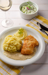 Paniertes und gebratenes Fischfilet mit Kartoffelpüree, Dillsauce und Zitrone