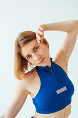 Close photo of a beautiful sports woman in a sports bra on a white background posing for the camera. Vertical