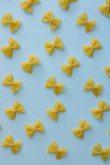Pasta farfalle random flat illustration on blue background. Raw farfalle pasta on colored background