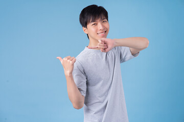 Young Asian man posing on blue background - Powered by Adobe