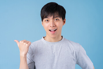 Young Asian man posing on blue background