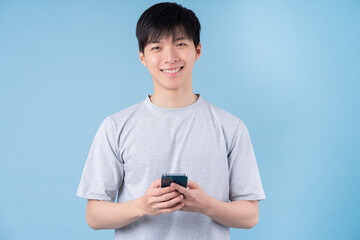 Young Asian man using smartphone on blue background