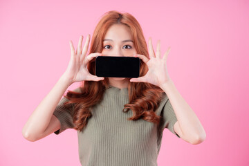 Young Asian woman using smartphone on pink background
