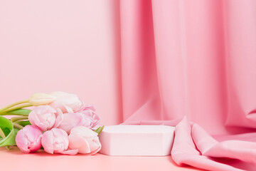 Podium with pink tulips and textile fabric drape at the background. Display for spring cosmetic or...