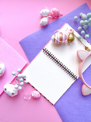 Pink Desktop. Notebook on the table with easter decorations. Frame border flat lay copy space top view. 