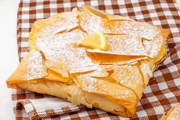 Sweet pastry bougatsa made from filo dough in the shape of an envelope sprinkled with powdered sugar.