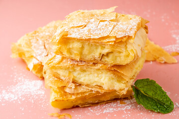 Pieces of sweet pie from philos pastry with cream top view on a dark background. Greek bougatsa sliced