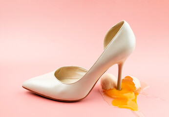 A woman's shoe crushed a chicken egg. The concept of female dominance. Concept photo.