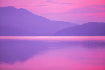 Sunrise time at lake or river with mountain on the background. in pink color tone.