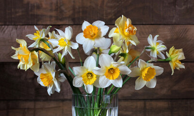 bouquet of different daffodils on a wooden background.
