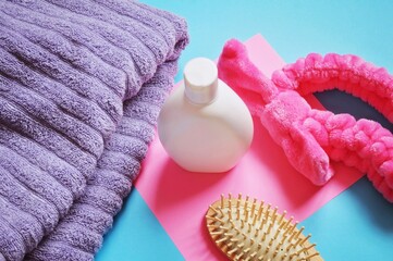 Lilac soft towel, shampoo bottle, wooden comb and cosmetic hair band for washing face. Bath...