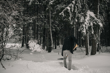A man clears snow in a winter forest