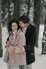 Happy young couple hugging in a snowy forest