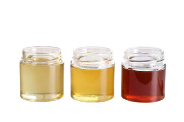 honey of different varieties in glass jars stands on a white background, an isolated object