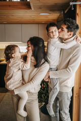 Young happy couple with two children hug and kiss