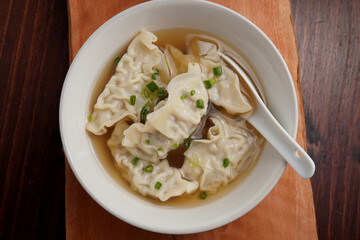 Pork dumplings boiled in clear water in a ceramic cup on a wooden table