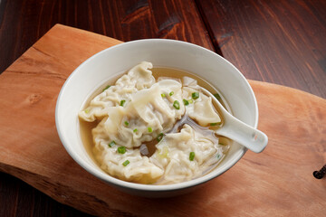 Pork dumplings boiled in clear water in a ceramic cup on a wooden table