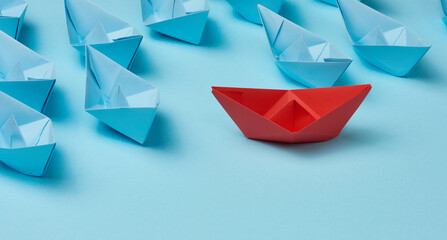 group of paper boats on a white background. concept of a strong leader in a team, manipulation of the masses, following new perspectives, collaboration and unification